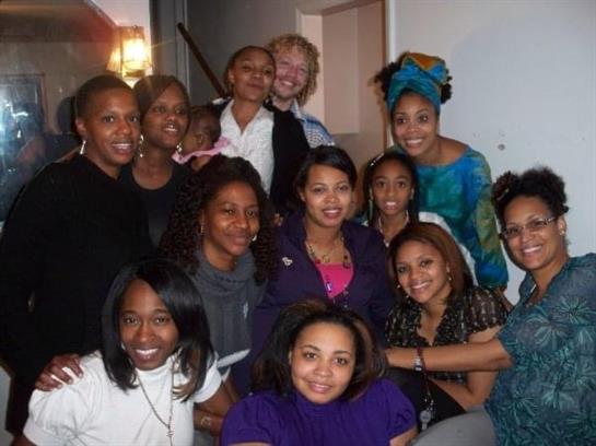 Women are smiling and posing together in a warm, inviting indoor environment filled with laughter.