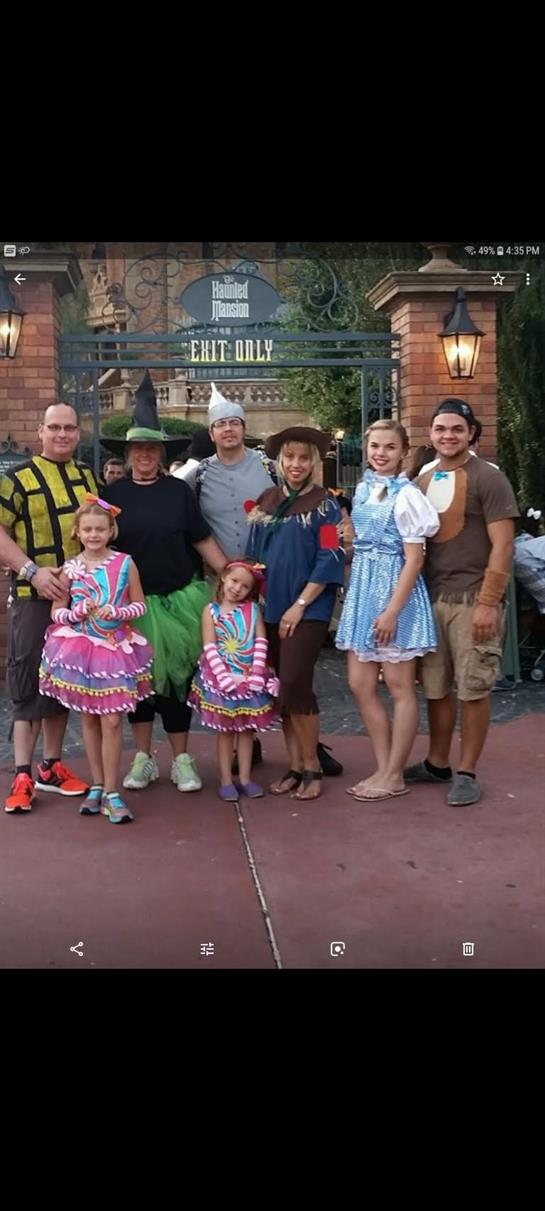 A lively group of friends and family in various costumes enjoys a themed celebration under lights.