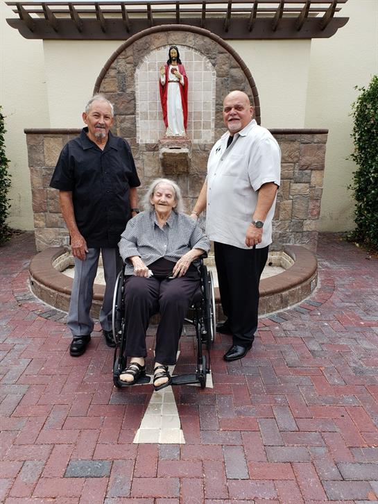Three family members share a moment in front of a shrine, highlighting family bonds and tradition.