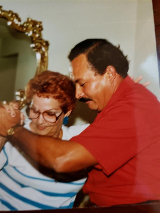 Two people enjoy a dance, sharing smiles and laughter in a cozy home atmosphere.