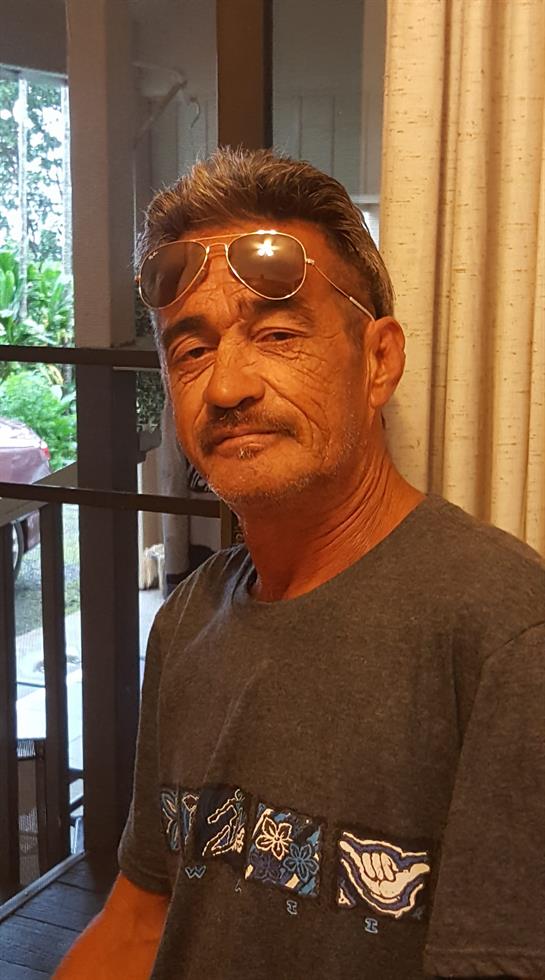 A man stands relaxed, wearing sunglasses.