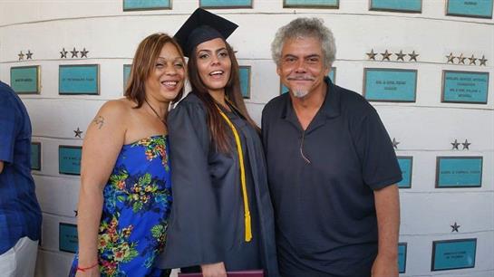 Family members proudly pose with a graduate wearing her cap and gown after the ceremony.