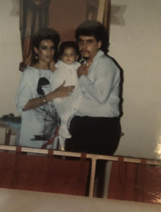 Parents hold their baby in a warm home environment with soft lighting, capturing a cherished moment.