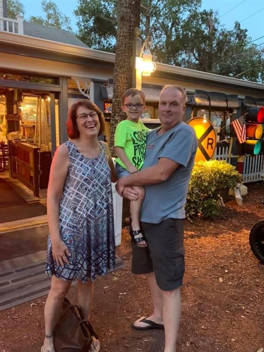 A joyful family stands together in front of a restaurant, enjoying their time in the evening air.