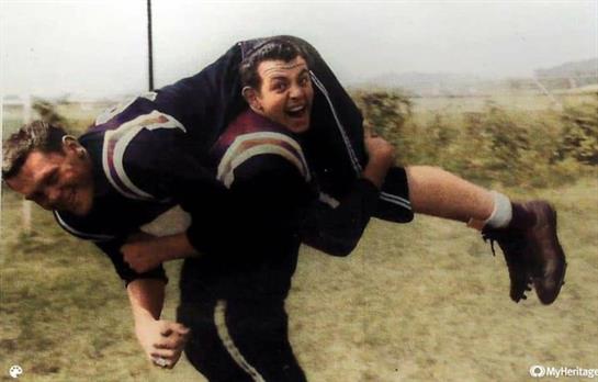 One athlete joyfully carries another on his back during an exciting outdoor challenge.