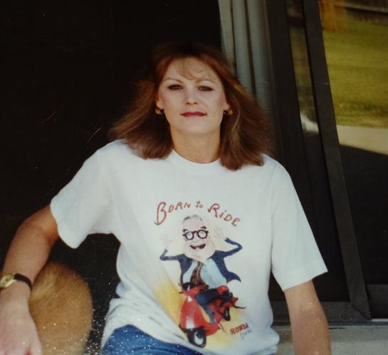 A woman is casually sitting on the steps of a building, enjoying the sunny weather.