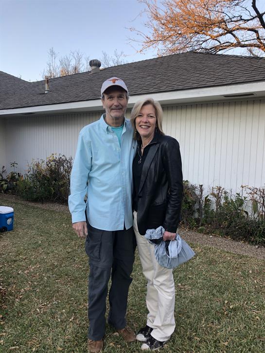 Two happy individuals pose for a photo in a backyard during a casual outdoor gathering.