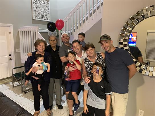 Family members gather together in a home, smiling and celebrating a joyful occasion with balloons.