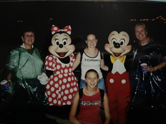 Families enjoy posing with popular characters in colorful outfits under bright lights.