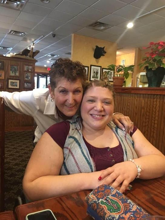 Two friends share laughter and warmth while sitting at a table in a welcoming restaurant.