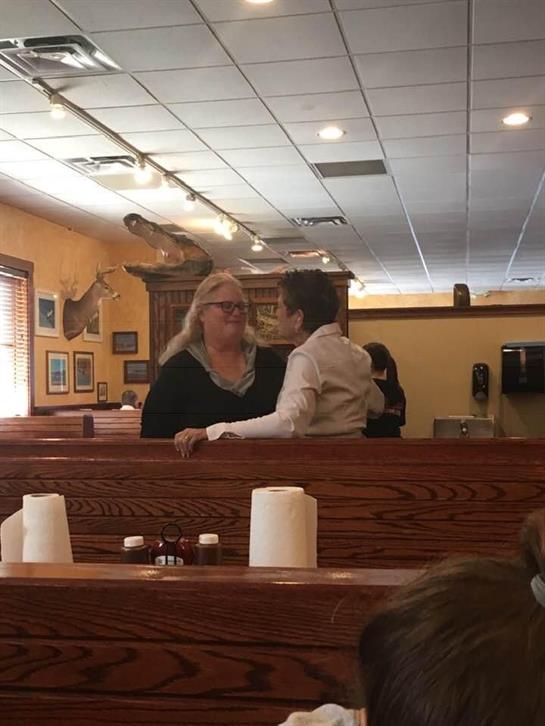 A woman and a child share a joyful moment in a cozy restaurant filled with wooden decor.