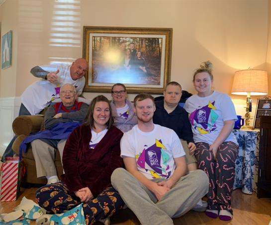 A joyful family enjoys time together in a warm living room, wearing matching shirts and lounging.