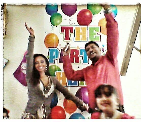Two adults joyfully celebrate at a birthday party with colorful decorations and balloons.