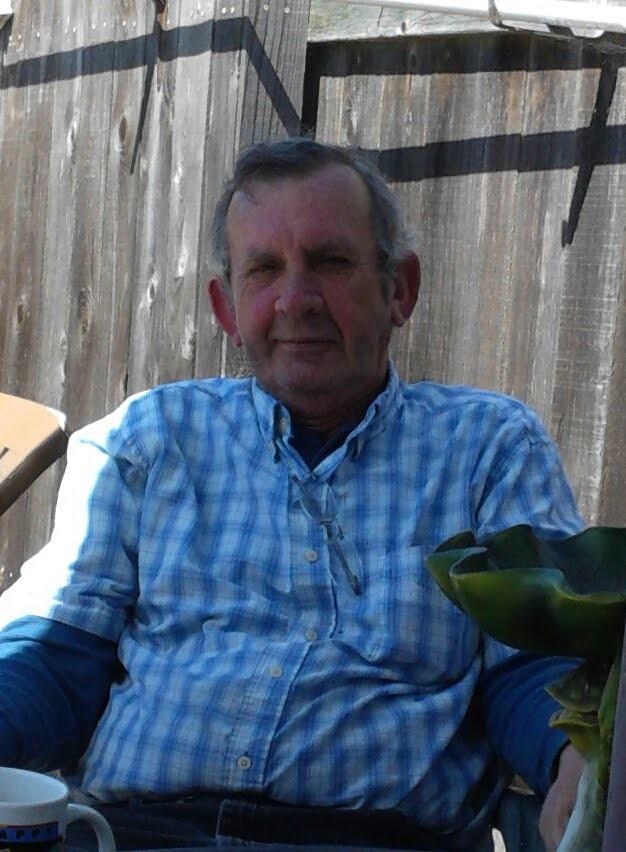 Senior man enjoys a peaceful afternoon outdoors sitting next to potted plants in sunshine.