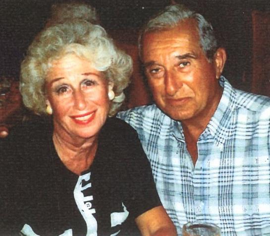 A cheerful couple smiles together at a table in a cozy restaurant.