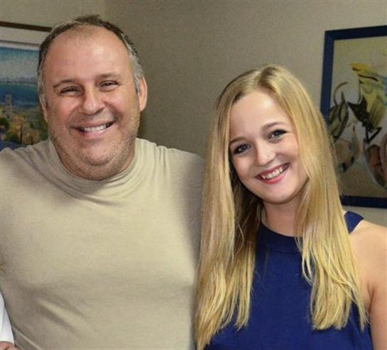 Two friends share laughter and smiles in a warm indoor environment, highlighting a joyful bond.