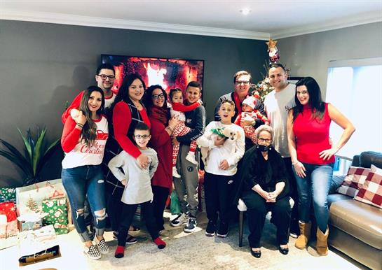Family members gather around a decorated Christmas tree, sharing laughter and holiday spirit.