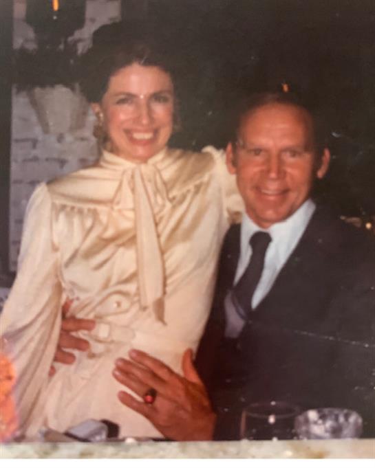 A cheerful couple embraces each other joyfully amid warm lighting and an intimate atmosphere.