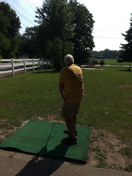 A man in casual clothing prepares to throw a disc in a spacious park on a sunny day.