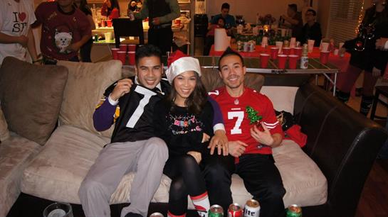 Friends gather joyfully in a decorated living room with drinks and laughter.