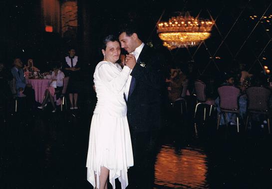 A couple dances romantically in a beautifully lit venue, celebrating a special occasion.