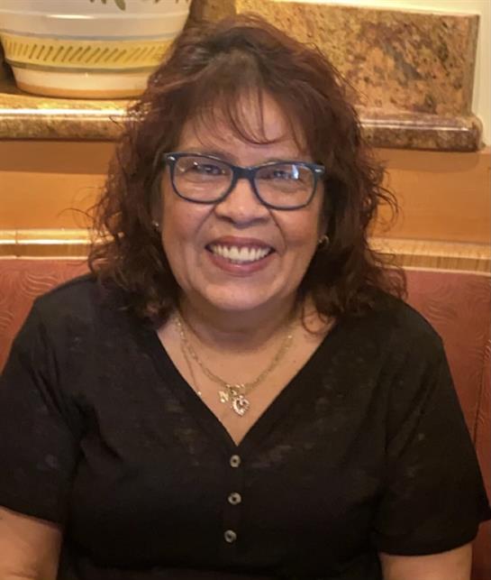 A joyful woman smiles while enjoying time with friends in a warm restaurant setting.