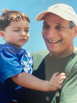 A joyful grandfather holds his grandson close while they share a moment at the beach.