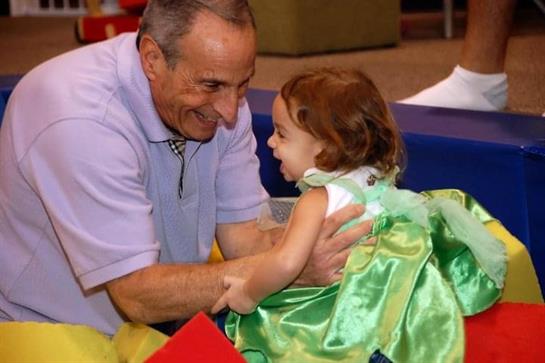 A grandfather and granddaughter share a joyful, playful bond in a vibrant setting.