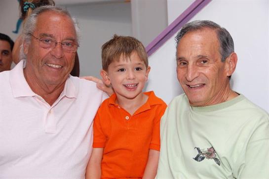 Two elderly men and a boy share smiles at a joyful family gathering.