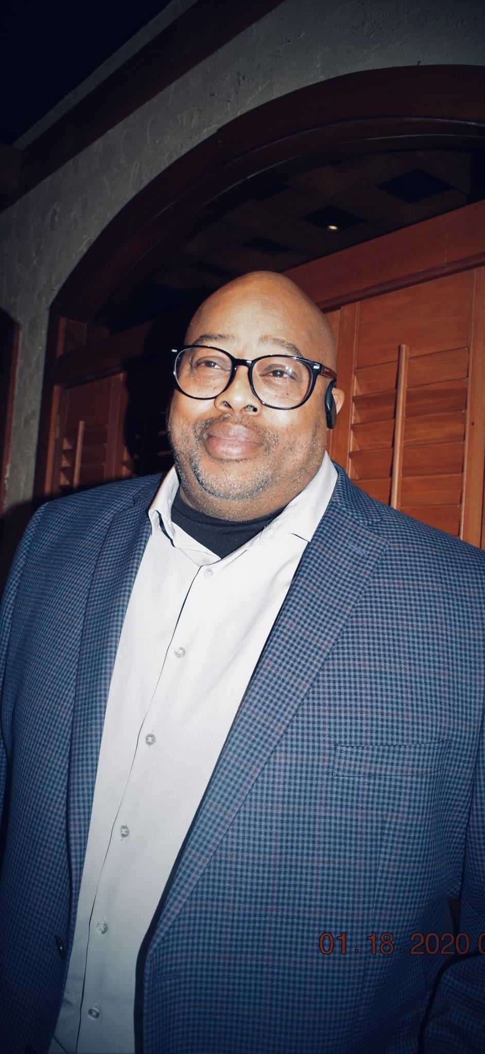 A man dressed in a blue suit joyfully engages with guests at a gathering, showcasing elegance.