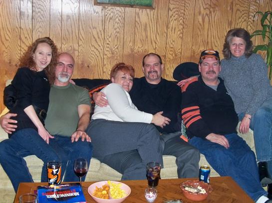 A group of friends relaxes together on a sofa, sharing laughs and snacks in a cozy space.