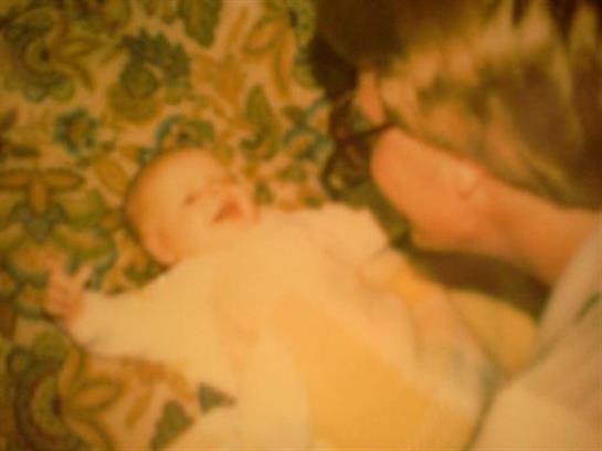 A joyful baby lies on a vibrant rug while interacting with a parent, sharing moments of happiness.