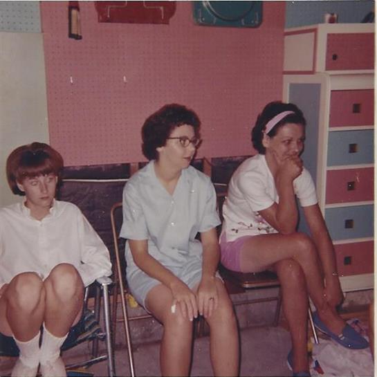 Three young girls are seated in a lively room filled with bright colors and playful decor.