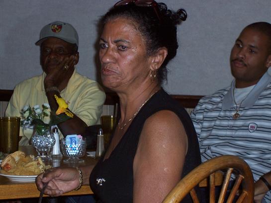 Several people engage over dinner, sharing laughter and conversation in a lively atmosphere.