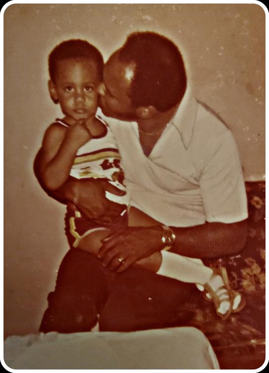 A father lovingly kisses his son while seated on a couch, radiating warmth and connection.