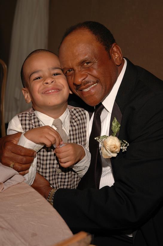 Grandfather and grandson smile together at a family gathering celebrating a special occasion.