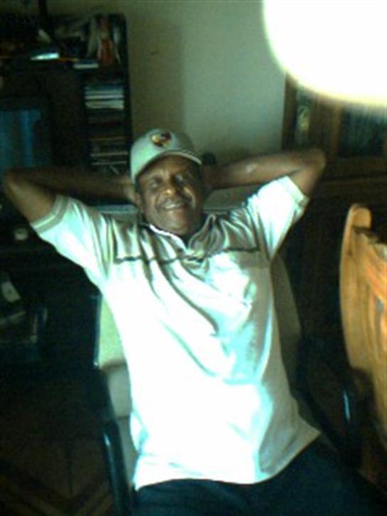 A proud elderly man enjoys his time, smiling and relaxing in a comfortable indoor setting.