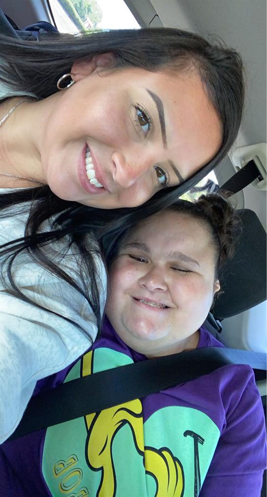 Two friends enjoy a cheerful moment in the car, smiling and embracing their time together.