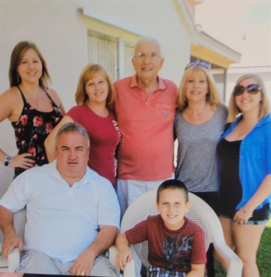 Group of family members enjoying time together, smiling and posing for a photo outside a house.
