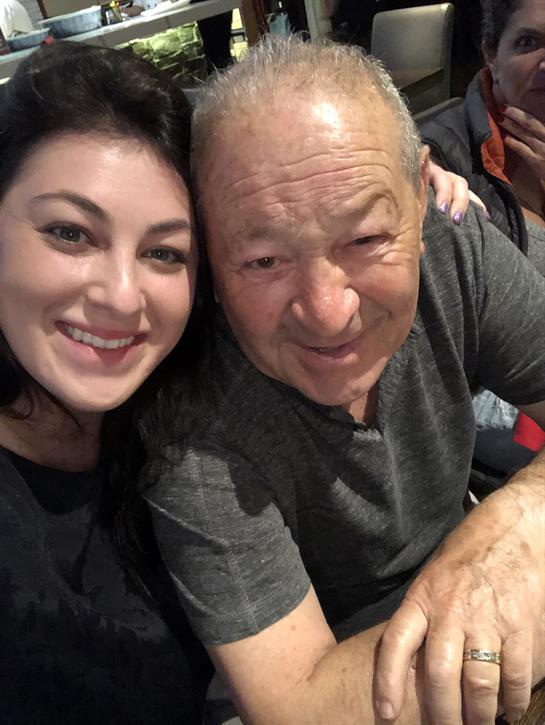 Two people are smiling closely together, sharing a happy moment during a family gathering.