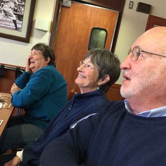Three friends share laughter and stories while seated at a cozy table in a cafe.