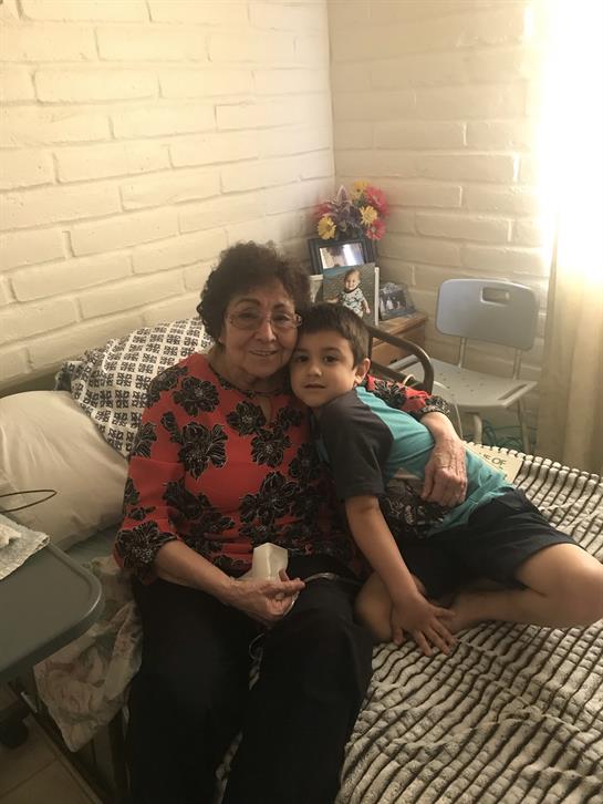 A grandmother shares a warm moment with her young grandson in a bright living space.