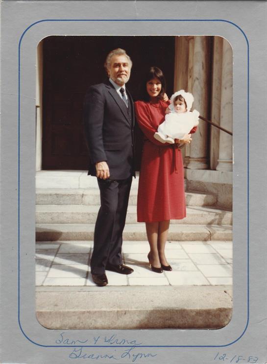A family stands proudly on steps with a baby dressed warmly, enjoying a joyful moment together.