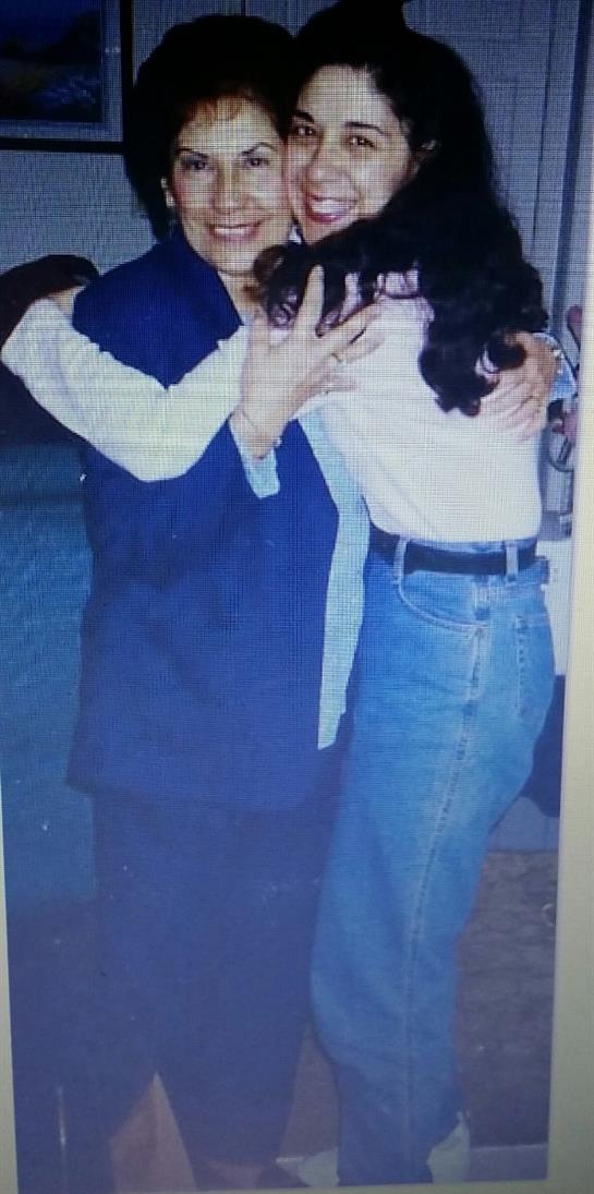 Two people share a joyful hug while dressed casually during a family gathering at night.
