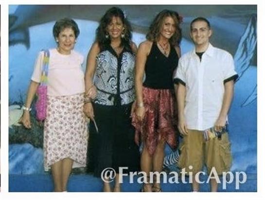 Four family members stand together in summer outfits, sharing a joyful moment at an amusement park.