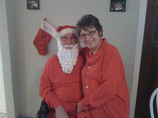 A joyful moment captured of a couple in holiday clothing celebrating together by a decorated wall.