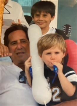 A cheerful family moment at the beach features children holding inflatable toys while smiling.
