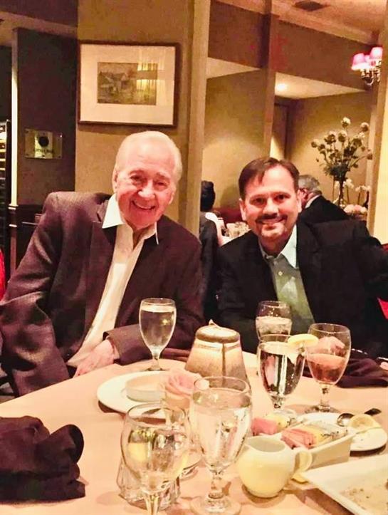 Two men at a well-decorated restaurant are enjoying a friendly conversation over dinner.