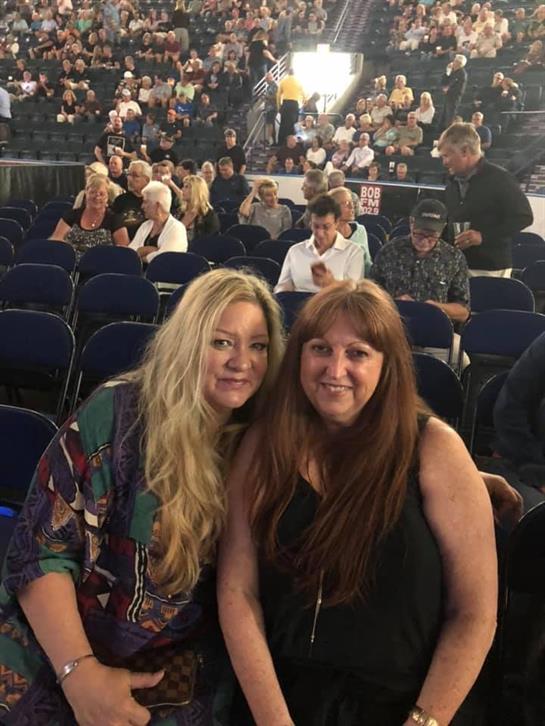 Two women pose for a friendly photo, excitedly waiting for the concert to begin.