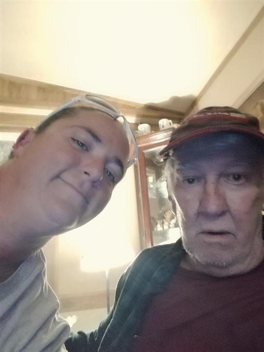 Two individuals share a moment, posing for a close selfie within a cozy indoor setting.